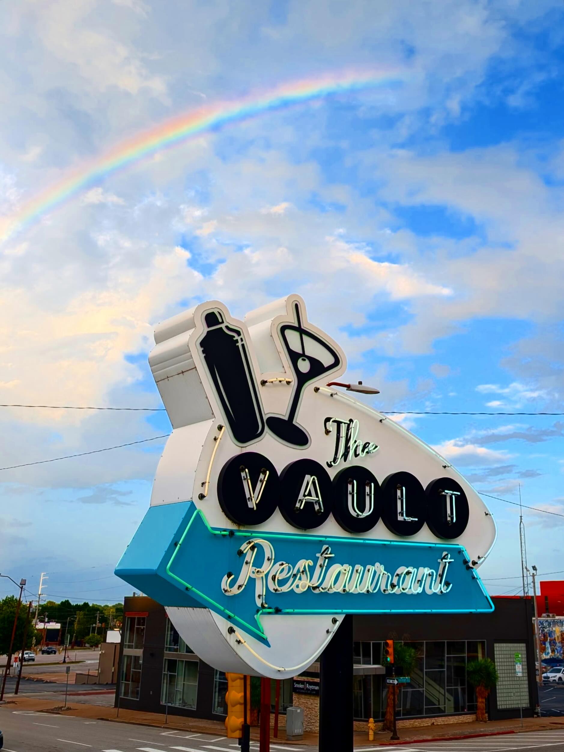 The Vault's neon sign with a cocktail shaker and martini glass against a Tulsa sky